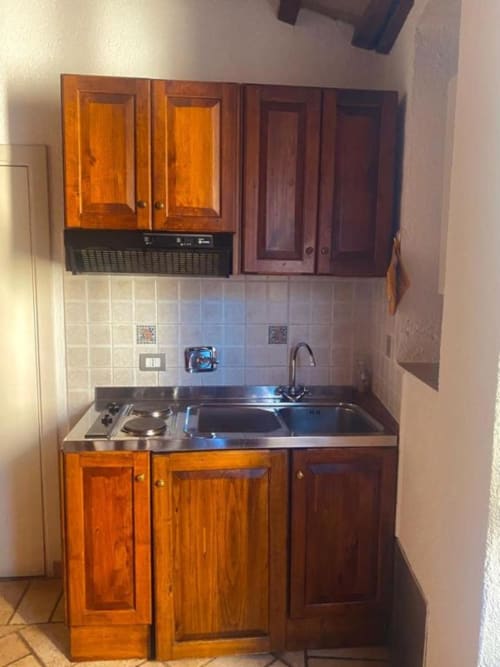 Piccolo angolo cottura nell'appartamento Residenza San Jacopo con mobili in legno, piano di lavoro in acciaio inox, fornelli e lavello