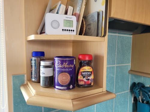 Wooden kitchen shelf in Jane's B&B apartment displaying coffee, hot chocolate, instant coffee and kitchen supplies with