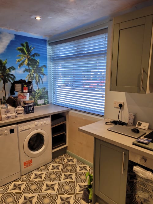 Modern laundry room with washing machine, work desk, and tropical mural at Jane's B&B apartment in Guisborough