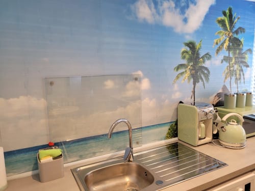 Modern kitchen sink with tropical beach backsplash in Jane's B&B apartment, Guisborough. Cream appliances and palm tree view