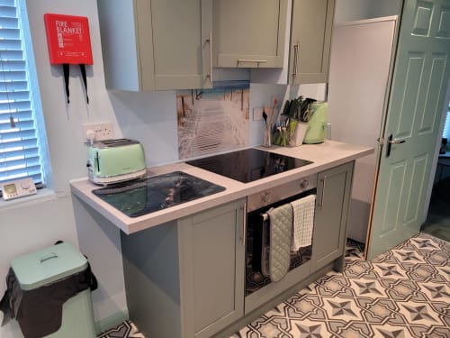 Modern kitchen in Jane's B&B apartment with sage green cabinets, induction cooktop, oven, and mint green toaster in