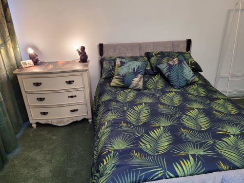 Modern bedroom at Jane's B&B in Guisborough featuring tropical palm bedding, white dresser, and grey carpet flooring