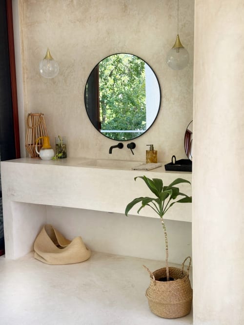 Lavabo moderno con espejo redondo en la cabaña Casa Tuch de Mérida, diseño minimalista y vegetación