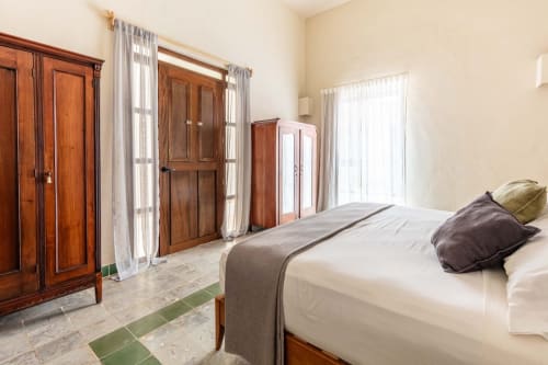 Luminoso dormitorio de la Casa Tuch B&B en Mérida con muebles de madera, ropa de cama blanca y vista a la piscina