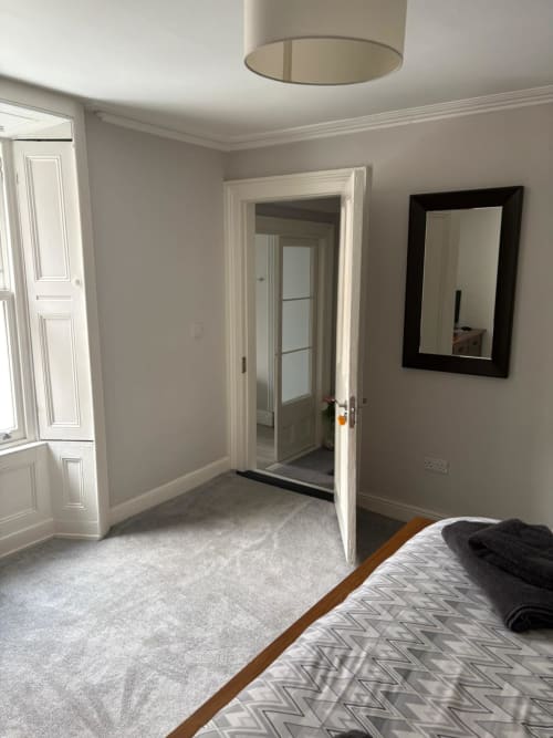 Spacious Super King bedroom at Eglinton Road Bray with ensuite door, black-framed mirror, and light carpet