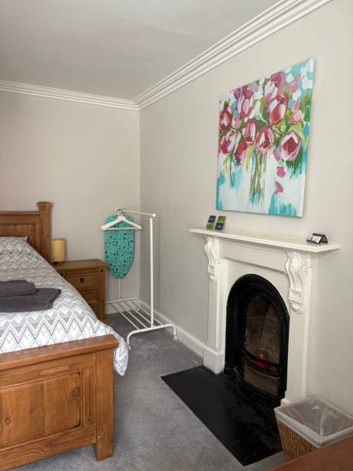 Cozy bedroom at Eglinton Road Bray B&B with wooden bed, fireplace, floral artwork, and modern amenities in Bray, Ireland