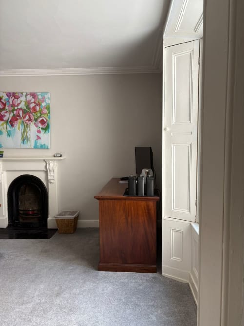 Elegant hotel room at Eglinton Road Bray with fireplace, wooden desk, white doors, and floral artwork