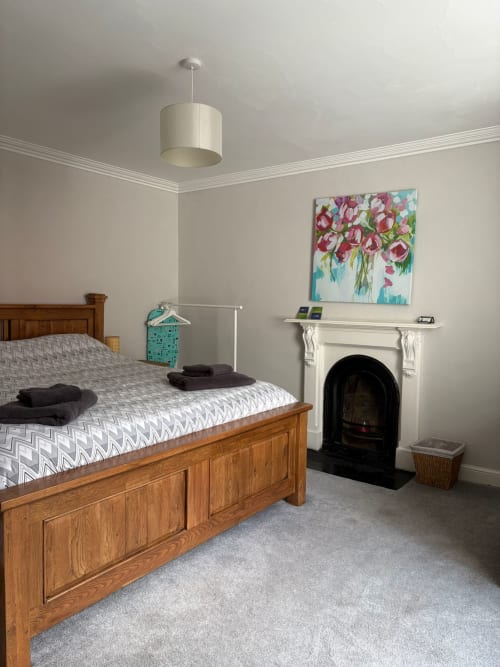 Super King bedroom at Eglinton Road Bray with wooden bed, fireplace, and floral artwork