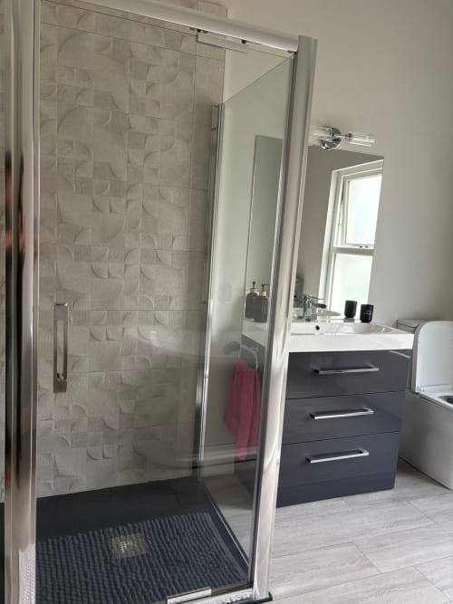 Modern bathroom at Eglinton Road Bray with walk-in shower, dark vanity, mirror, and white toilet