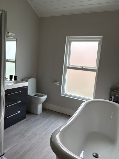 Modern bathroom at Eglinton Road Bray B&B featuring freestanding bathtub, vanity, toilet, and skylights