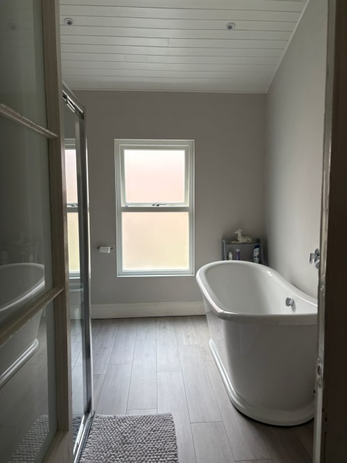Modern bathroom with freestanding bathtub, shower, large window, and gray walls at Eglinton Road Bray B&B in Bray, Ireland