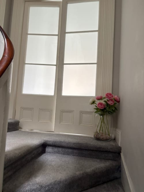Bright bedroom at Eglinton Road Bray with French doors, gray bedding, pink roses in vase, and elegant furnishings