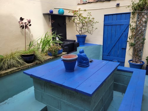 Vibrant blue courtyard at Jane's B&B villa with potted plants, decorative spheres, and dining area in Guisborough