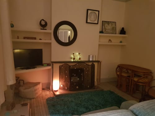 Cozy sitting room at Jane's B&B villa with TV, fireplace, round mirror, and green rug in Guisborough