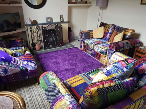 Colorful bedroom at Jane's B&B in Guisborough with purple rug, patchwork beds, and cozy sitting area