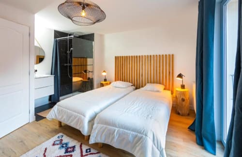 Chambre moderne à la Maison de Sophie B&B à Rencurel avec lits jumeaux, tête de lit en bois et salle de bain attenante