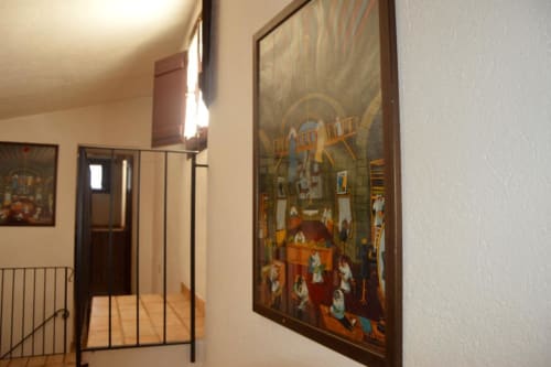 Corridoio della Residenza San Jacopo a Spello con opere d'arte tradizionali incorniciate e scala di accesso alle camere