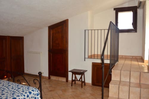 Ampia camera da letto con pavimento in cotto, porte in legno e zona soppalco presso Residenza San Jacopo a Spello