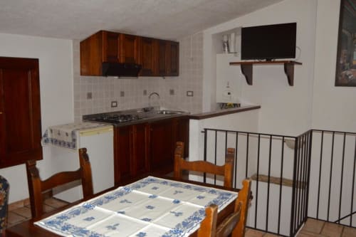 Angolo cottura del B&B di Spello con tavolo da pranzo, mobili in legno, fornello e pavimento in cotto