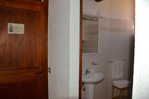 Bagno dell'appartamento Residenza San Jacopo a Spello con lavabo su colonna, toilette, specchio e zona doccia