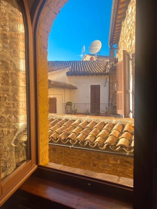 Vista dalla finestra dell'appartamento Residenza San Jacopo a Spello: tetti in terracotta e edifici storici in pietra