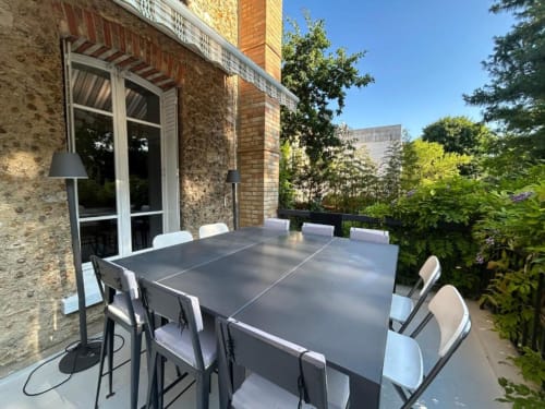 Outdoor dining terrace at Villa Saint-Hilaire with gray table, white chairs, and garden views in Colombes