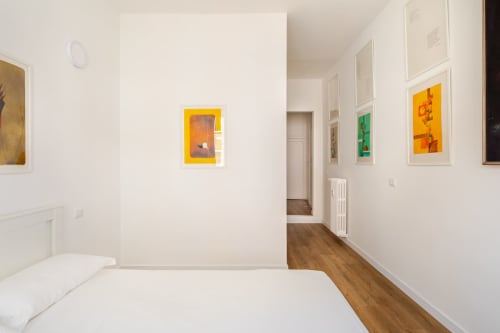 Appartamento Modern Art Gallery a Roma con letto bianco, pavimenti in legno e colorati quadri incorniciati alle pareti