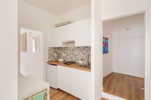 Cucina moderna con mobili bianchi, piano in legno, piastrelle decorate e piano cottura a gas nell'appartamento Art House Roma
