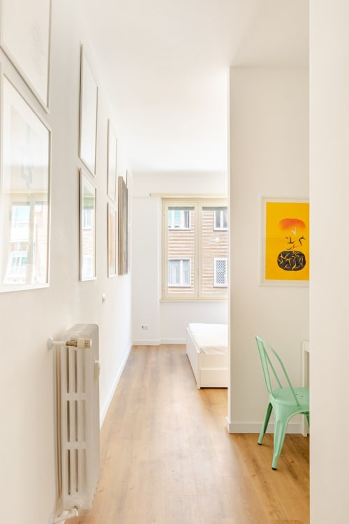Luminoso corridoio moderno nell'appartamento Art House Roma con opere d'arte incorniciate, quadro giallo contemporaneo e luce naturale