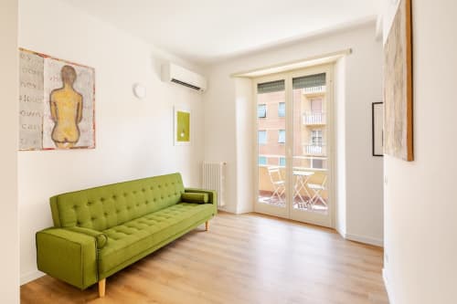 Appartamento Modern Art Gallery a Roma con divano verde, pavimenti in legno e balcone con vista sulla città