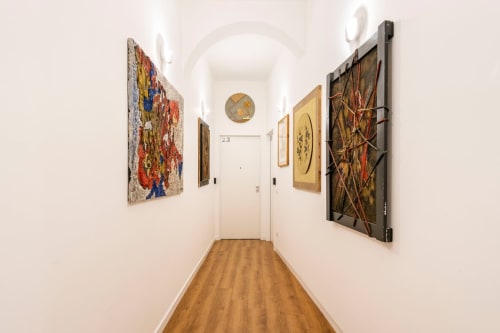 Stretto corridoio dell'appartamento Art House Roma con opere d'arte su pareti bianche e pavimento in legno