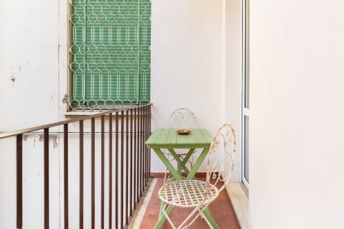 Accogliente balcone dell'appartamento Art House Rome con tavolo verde, sedia bianca e elegante grata decorativa
