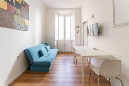Appartamento Modern Art a Roma con divano blu, pavimenti in legno, TV, area lavoro e luce naturale da vetrate
