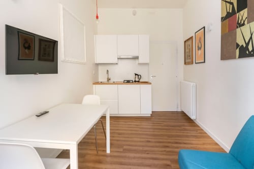 Appartamento Art House Roma: zona living open-plan con cucina bianca, tavolo da pranzo, TV, pavimenti in legno e arredamento moderno