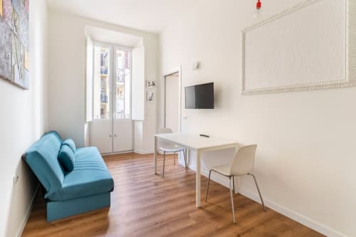Appartamento Art House a Roma con divano blu, area di lavoro, TV e pavimenti in legno