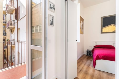 Camera da letto moderna in appartamento Art House Roma con letto, balcone, opere d'arte e pavimenti in legno