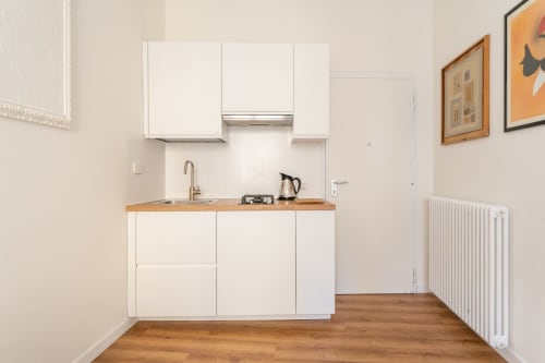 Cucina moderna bianca con piano in legno nell'appartamento Art House a Roma, fornello a gas, lavello e pensili