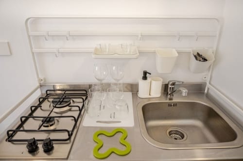 Cucina compatta in appartamento romano con fornello a gas, lavello e organizzatore di stoccaggio bianco