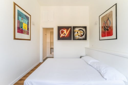 Camera da letto moderna ad Art House Rome con letto bianco, opere d'arte incorniciate e vivaci pop art su pareti color crema