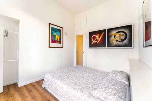 Camera da letto moderna all'Art House Roma con letto, pavimento in legno, opere d'arte colorate e porta gialla