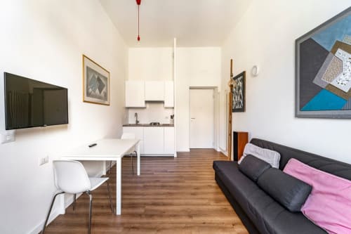 Appartamento Modern Art House a Piazza del Popolo Roma: divano nero, angolo cucina, zona lavoro e TV a parete.