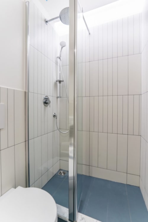 Bagno moderno con cabina in vetro, soffione a pioggia e doccetta manuale nell'appartamento Art House a Roma