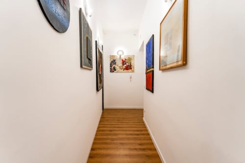 Corridoio della Art House Rome con pavimento in legno, pareti bianche e galleria di opere d'arte incorniciate vicino all'appartamento di Piazza del Popolo