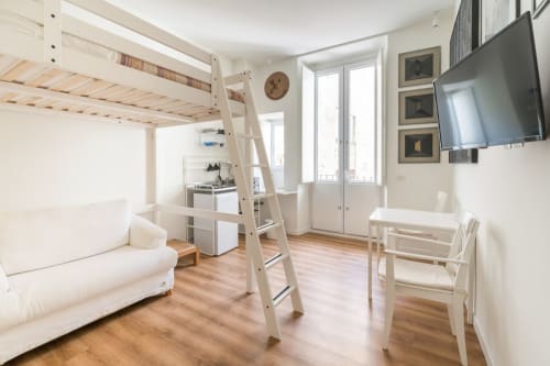 Luminoso monolocale moderno a Roma con letto a soppalco, arredamento bianco, angolo cottura, TV e porte finestre