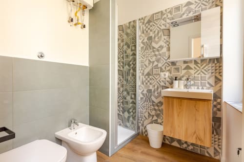 Bagno moderno nell'appartamento Art House Roma con rivestimenti geometrici, mobile legno, doccia e bidet