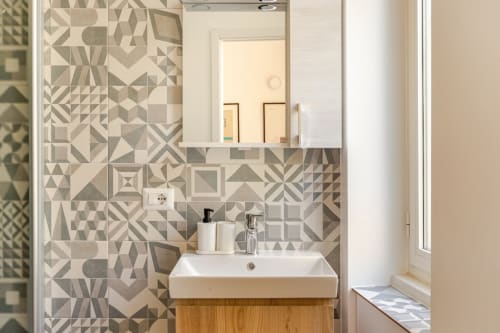 Bagno moderno dell'Art House Rome con piastrelle geometriche, lavandino bianco, mobile in legno e specchio in Policlinico
