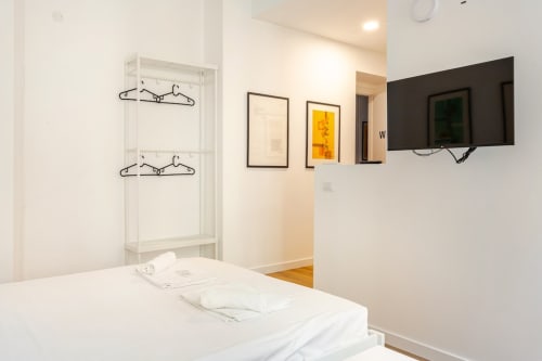 Camera da letto moderna all'Art House Rome con letto bianco, TV a parete, quadri incorniciati e appendiabiti.