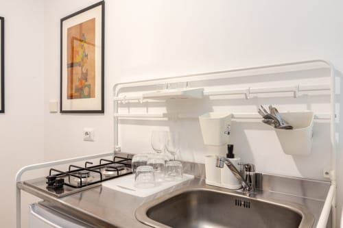 Moderna cucina nel appartamento romano con fornello a gas, lavello, ripostiglio bianco e quadro incorniciato