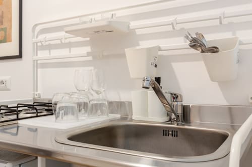Lavabo moderno della cucina con organizzatori bianchi, bicchieri e utensili presso Art House Roma