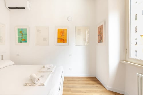 Camera da letto minimalista moderna all'Art House Rome con arte astratta incorniciata, biancheria bianca, pavimenti in legno e luce naturale abbondante